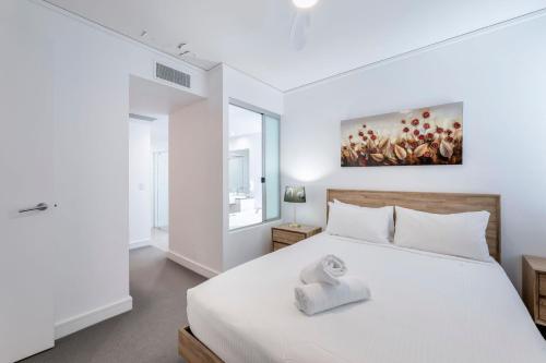 a bedroom with a white bed and a painting on the wall at C Bargara Unit 101 in Bargara
