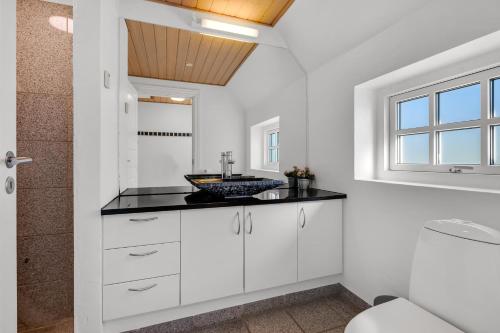 a white bathroom with a sink and a mirror at Feriehus 2033 in Ulfborg