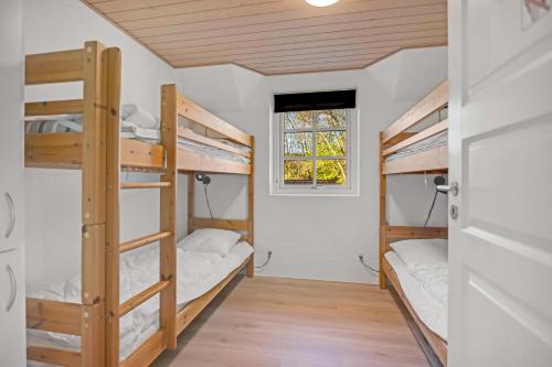 a room with three bunk beds and a window at Feriehus 2033 in Ulfborg