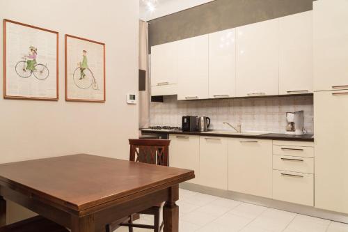 ミラノにあるPliniusの白いキャビネットと木製テーブル付きのキッチン