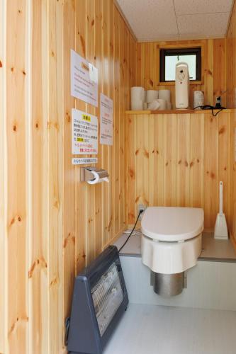 a wooden bathroom with a toilet and a tv at GRAMPING STAY TOMAMU in Tomamu