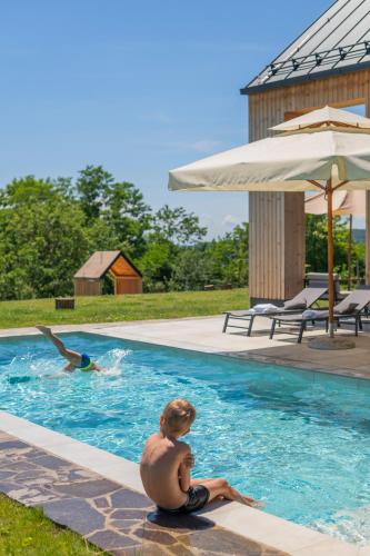 a boy sitting on the edge of a swimming pool at Blacksmith house - SPA, Heated outdoor pool, Kids zone in Varaždinske Toplice