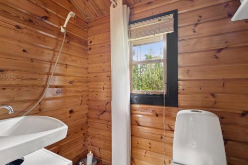a bathroom with wooden walls and a toilet and a window at Peaceful Holiday Home Close To Nature in Glesborg