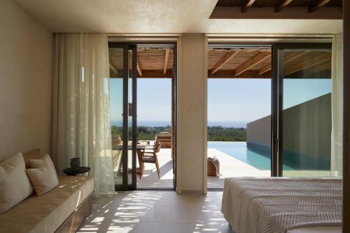 a bedroom with a bed and a view of a pool at Memorias Villas and Suites in Vasilikos