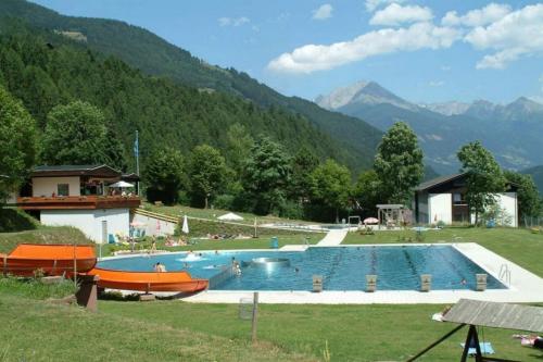 ein großer Pool auf einem Feld mit Bergen im Hintergrund in der Unterkunft Hotel Gletschermühle in Flattach