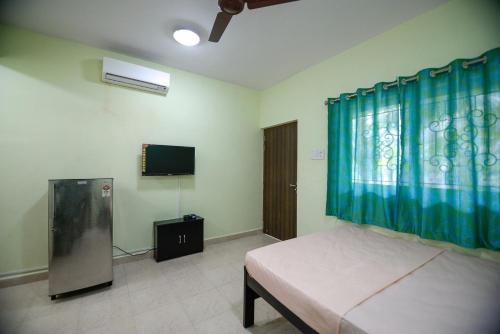 a bedroom with a bed and a flat screen tv at Sunshine Park Homes in Colva
