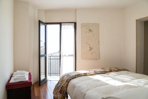 Casa Gemei في Mello: غرفة نوم بسرير ونافذة كبيرة