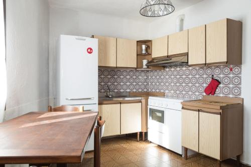 Casa Gemei في Mello: مطبخ مع ثلاجة بيضاء وطاولة خشبية