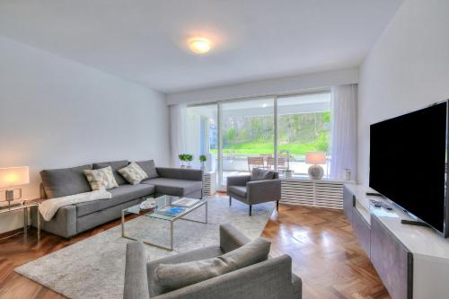 a living room with a couch and a tv at Residenza Parco Carona with Lake-View - Happy Rentals in Lugano