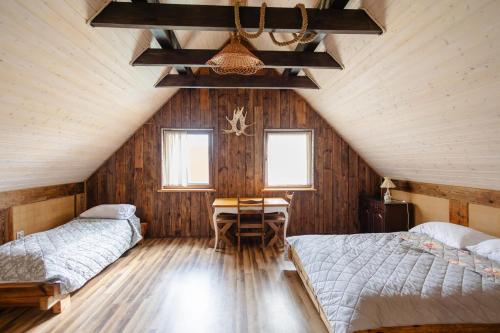 a attic bedroom with two beds and a table in it at Klinwdzydze in Wdzydze Tucholskie