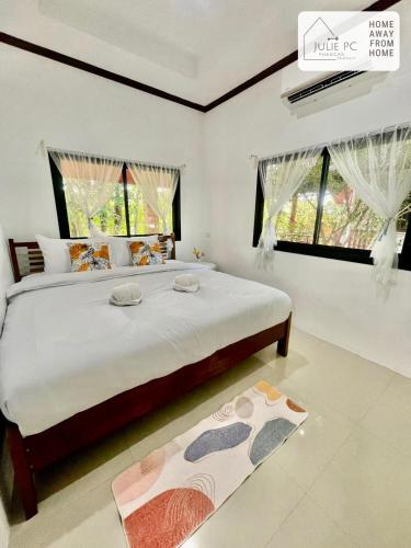 a bedroom with a large bed and two windows at Temple House by Julie PC in Ko Phangan