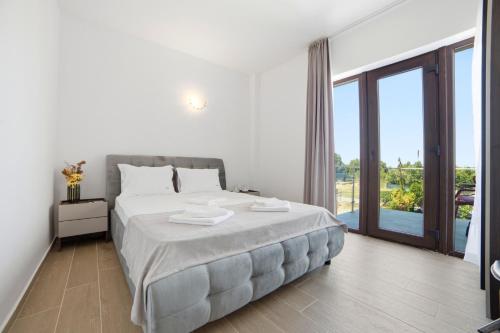 a white bedroom with a bed and a large window at InWaves in Vama Veche