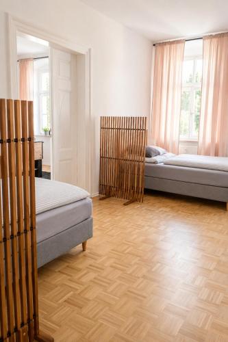 two beds in a room with wooden floors and windows at Gera Apartment Green in Gera