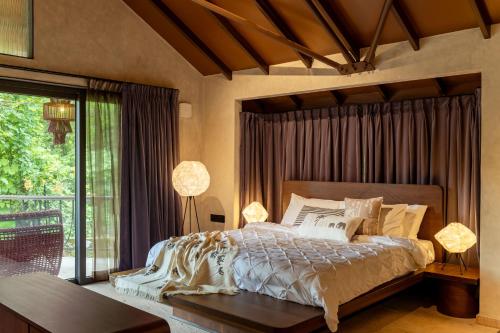 a bedroom with a large bed and a balcony at SAMA The Silver Creek in Bogmalo