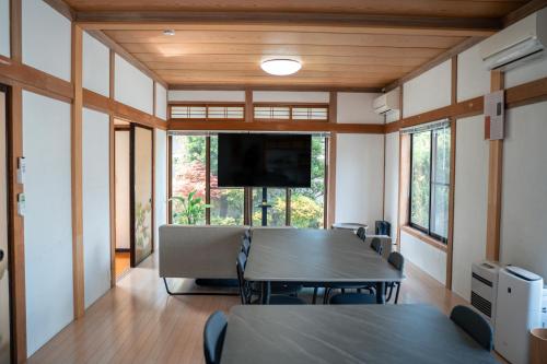 a room with a table and chairs and a flat screen tv at The Alpen House Omachi in Omachi