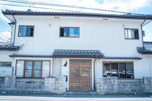 a white house with a brown door and windows at The Alpen House Omachi in Omachi