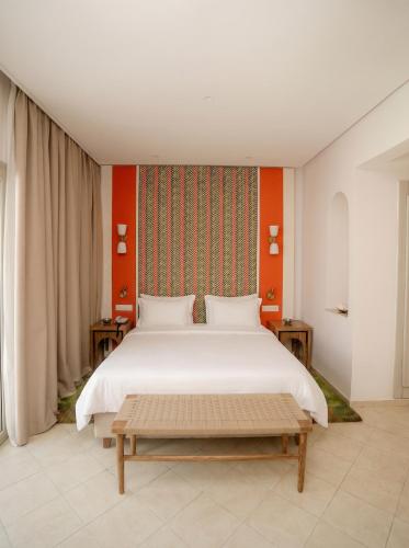 a bedroom with a large white bed and orange wall at Seabel Alhambra Beach Golf & Spa in Port El Kantaoui