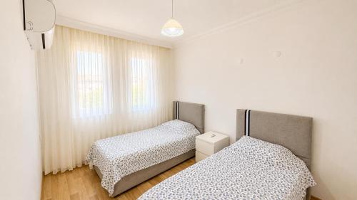 two twin beds in a room with a window at Fethiye Merkezde Lüx Daire in Fethiye