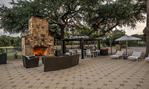 a patio with a stone fireplace and chairs and umbrellas at Hampton Inn & Suites Boerne in Boerne