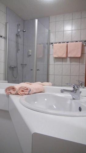a bathroom with a sink and a shower with pink towels at Hotel Bigger Hof - Wirtshaus Platzhirsch am Jahnplatz in Olsberg