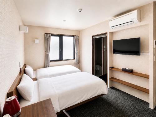 a hotel room with two beds and a flat screen tv at Floral Hotel Mari-Kyoto in Kyoto