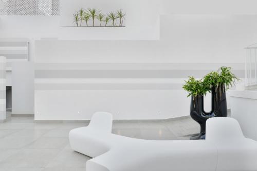 a white living room with a white chair and plants at Hotel Cerere in Paestum