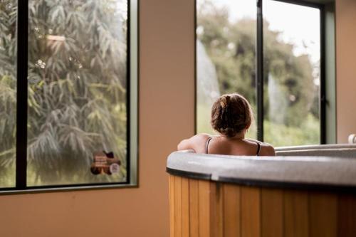 a woman sitting in a tub looking out a window at Tasman Holiday Parks - Wanaka in Wanaka