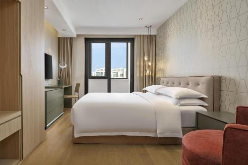 a bedroom with a large white bed and a television at Hyatt Place Shanghai Lingang in Zhenghai