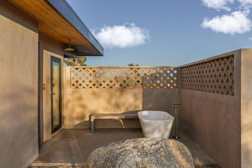 a patio with a bench and a rock at Sand Tulum Retreat w Pool Spa in Yucca Valley