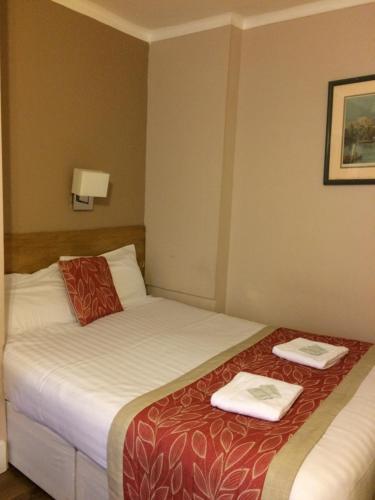 a hotel room with two beds with towels on them at The Grapevine Hotel in London
