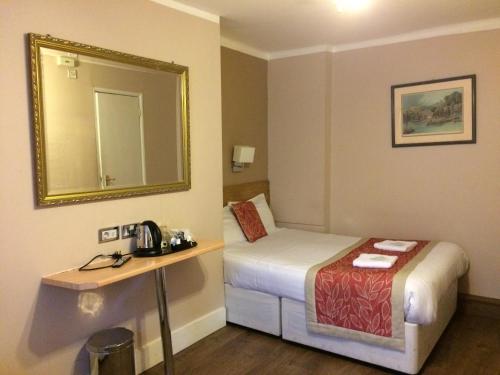 Habitación de hotel con cama y espejo en The Grapevine Hotel, en Londres