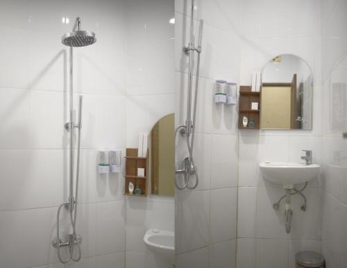 a white bathroom with a shower and a sink at The Garuda Villa and Restaurant in Bedugul