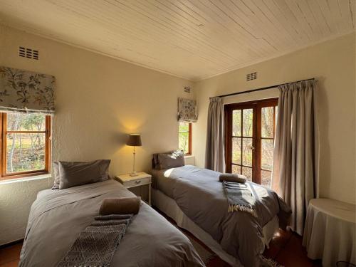 a bedroom with two beds and a window at Ntsinini Trout & Leisure Farm in Waterval Boven