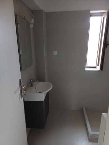 a white bathroom with a sink and a window at Valimitika beach house - Just 150m from the beach in Valimítika