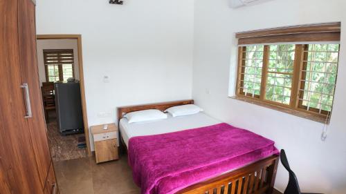 a bedroom with a bed with a purple blanket at BIKI'S PALM VILLA in Kaduturutti