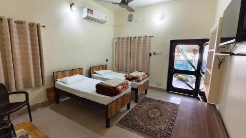 a bedroom with two beds and a window and a table at Iora Guest House in Bharatpur