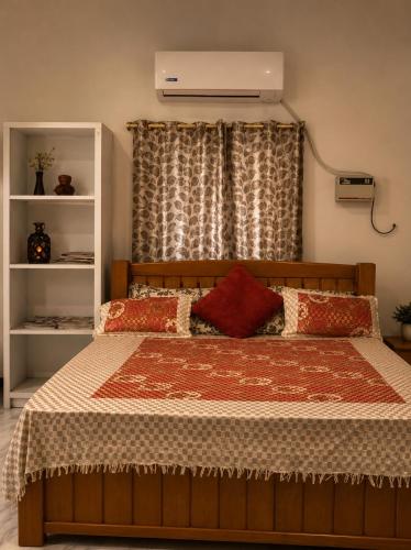 a bedroom with a bed with a red pillow at AUM VILLA Homestay in Pondicherry and Auroville in Puducherry Airpoert
