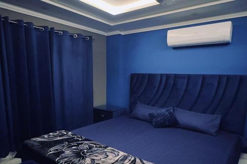 a blue bedroom with a bed with a blue wall at Bahria 777 Luxury Apartment in Lahore