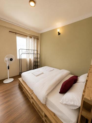 a bedroom with a large bed with white sheets and red pillows at Nirva Chey in Kathmandu