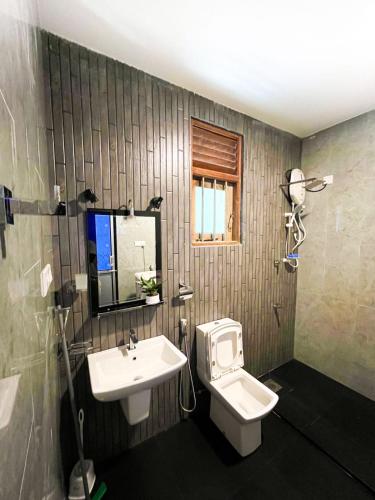 a bathroom with a sink and a toilet and a mirror at Bule Bells Villa in Matara