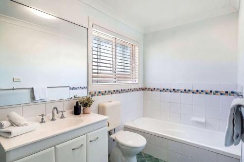 a white bathroom with a tub and a toilet and a sink at 5-41 Park Street in Evans Head