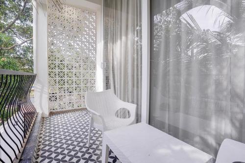 a porch with a white chair and a window at FabHotel JM Residency in Mandrem