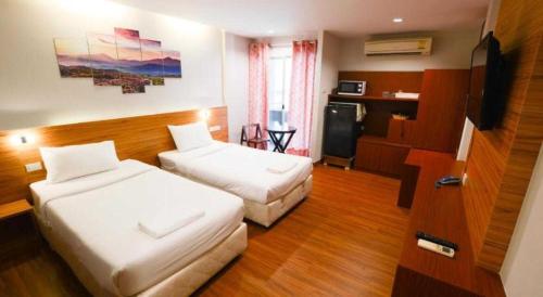 a hotel room with two beds and a television at Collection O Thaiphiphat House Silom in Bangkok