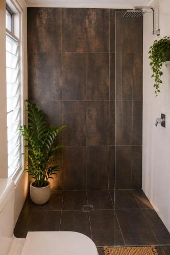 a bathroom with a shower with a plant at Bayhaven Lodge in Byron Bay