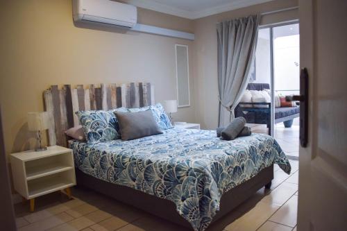 a bedroom with a bed with blue sheets and a window at Perfect holiday destination! in Jeffreys Bay