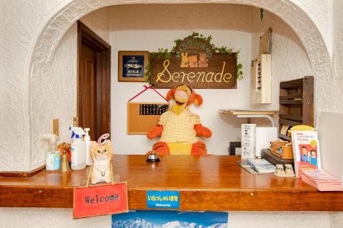 a cat sitting on a counter with a stuffed animal at Pension Serenade in Hakuba