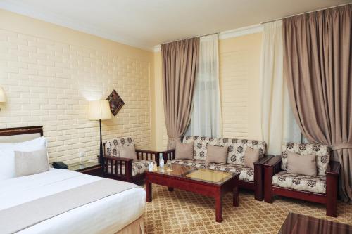 a hotel room with a bed and a table and chairs at Hotel Grand Samarkand Superior - A in Samarkand