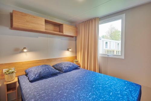 a bedroom with a blue bed and a window at Siblu de Tol in Nunspeet