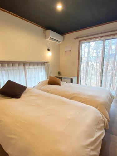 two white beds in a room with a window at Villa Mon Petit Nid Komoro in Komoro