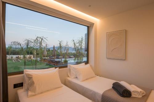 two beds in a room with a large window at Infinite View Villa in Platanias